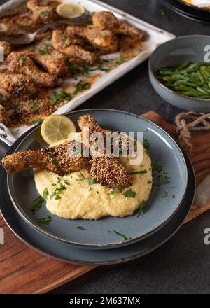 Sesame chicken drumsticks marinated with harissa sauce and topped sesame seeds. Served ready to eat on kitchen table Stock Photo
