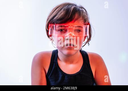 Thoughtful kid in orange smart goggles exploring virtual reality isolated on white background Stock Photo