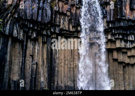 Picturesque view of Svartifoss waterfall falling from rocky cliff with splashing water located in Iceland Stock Photo