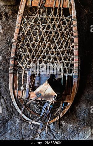 Wicker antique snowshoes with various metal details hanging on stony wall in daytime Stock Photo