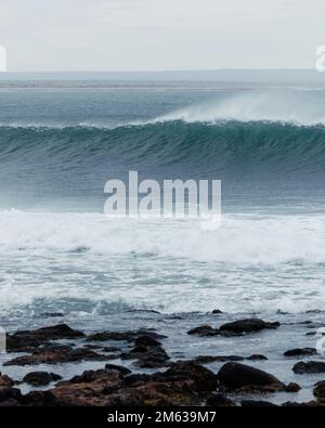 Powerful wave rolling over sea against cloudy sky in Cabo Raso, Argentina Stock Photo
