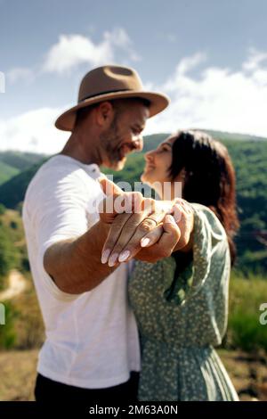 Soft focus of hands of young man in casual clothes and woman with wedding ring on finger while spending time in mountains looking at each other Stock Photo