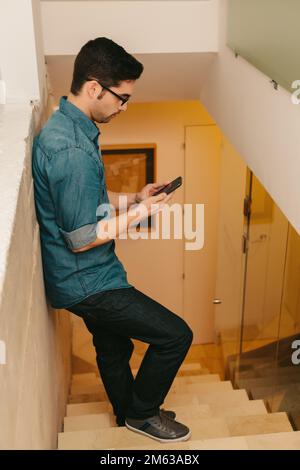 Young Man standing on a Ladder Using his Mobile Phone Stock Photo