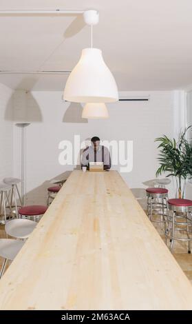Black Man working alone with a Digital Tablet on a Wooden Table Stock Photo