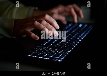 Hands of anonymous person typing on laptop keyboard at night, close up. Cyber security concept Stock Photo