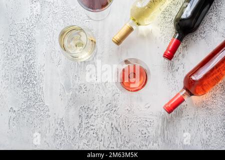 Red, rose and white wine bottles and different wine glasses on concrete background with copy space. Top view. Stock Photo
