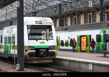People enter the train carriage on the railway platform of Helsinki Central Station. Helsinki Central Station is the main station for commuter rail and long-distance trains departing from Helsinki, Finland. Stock Photo