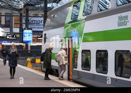 People enter the train carriage on the railway platform of Helsinki Central Station. Helsinki Central Station is the main station for commuter rail and long-distance trains departing from Helsinki, Finland. Stock Photo