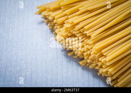 Yellow Italian spaghetti on blue background food and drink concept. Stock Photo