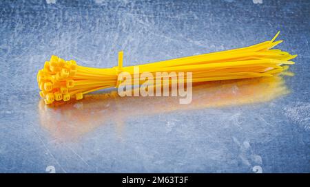 Yellow plastic self-locking cable ties on metallic background construction concept. Stock Photo