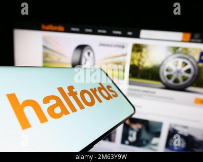 Smartphone with logo of British retail company Halfords Group plc on screen in front of business website. Focus on center of phone display. Stock Photo