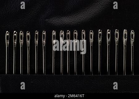 A set of needles for sewing fabric by hand on black background. Stock Photo