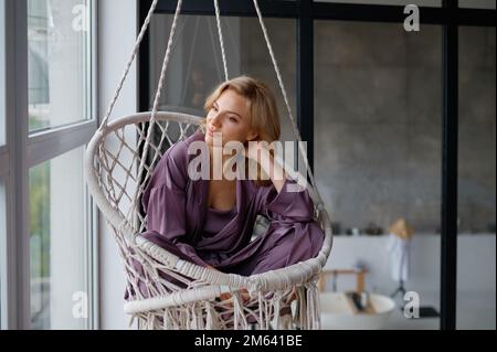 Woman rest in hanging wicker chair at home Stock Photo