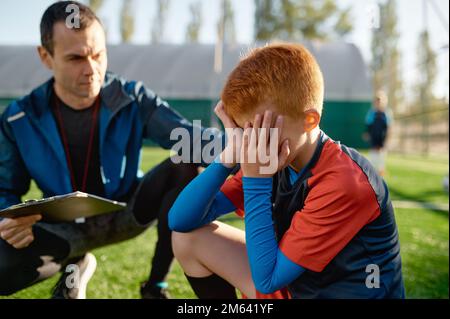 Coach comforting crying little soccer player after missed goal Stock Photo