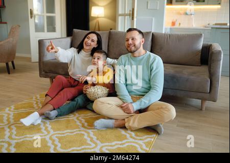 Amazed parents and curious kid watching tv program at home Stock Photo