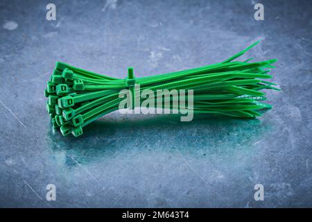 Green plastic self-locking cable ties on metallic background construction concept. Stock Photo