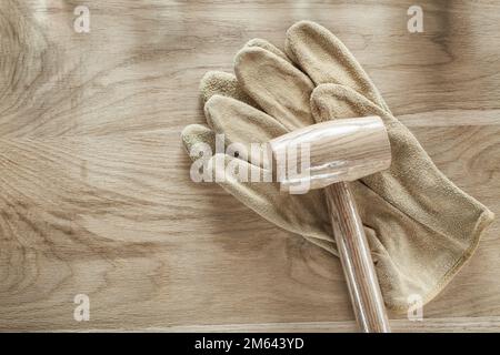 Leather protective gloves lump hammer on wooden board. Stock Photo