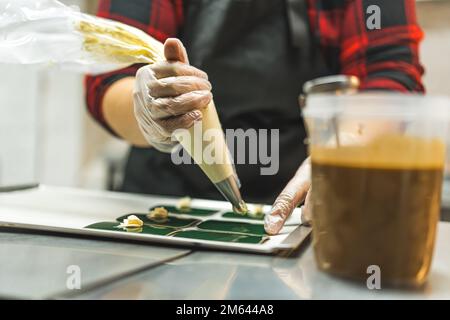 Pastry chef using pastry bag filled with white buttercream frosting. Bakery goods in preparation. High quality photo Stock Photo
