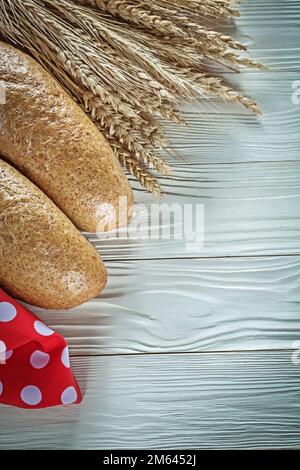 Long loaf wheat ears red tablecloth on white board. Stock Photo