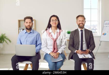 Portrait of positive diverse office colleagues using different gadgets in their work. Stock Photo