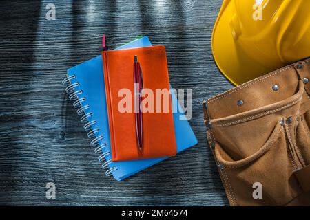 Notebooks pen safety cap leather tool belt on wooden board. Stock Photo