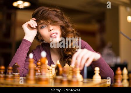 Woman playing chess indoor and thinking position, find winning move, strategy. Stock Photo