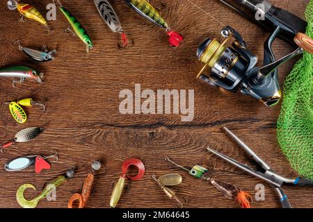 Fishing theme. Frame with reel, rod, fishing buoy, compass, feeder, knife  and on wooden background. Free space Stock Photo - Alamy