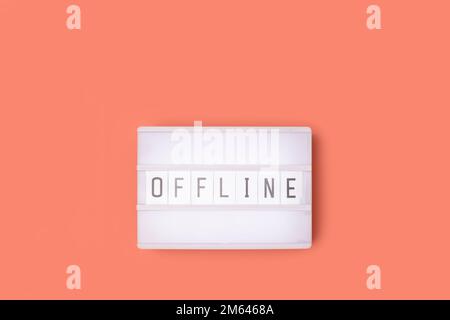 Word Offline. White lightbox with letters on a coral colored background. Stock Photo