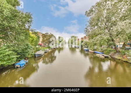 a canal with boats on the water and trees in blooming along the river, surrounded by lush green foliage Stock Photo