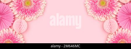 Banner with frame made of gerbera flowers, tissue paper fans and balls on a pink background. Stock Photo