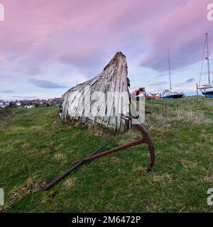 Upturned Herring boats used as storage sheds on Lindisfarne Island, the coast of Northumberland northern England, UK, GB. Stock Photo