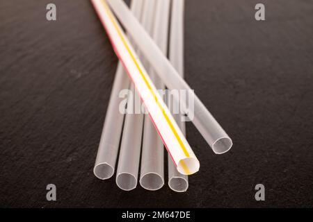 Several plastic straws for cocktails on slate stone, macro. Stock Photo