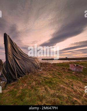 Upturned Herring boats used as storage sheds on Lindisfarne Island, the coast of Northumberland northern England, UK, GB. Stock Photo