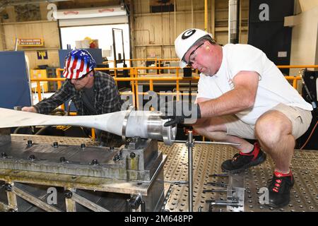 Larry Richardson, right, and Michael Bodrey, both 573rd CMXS machinists, mount a C-130H aircraft propeller to a Makino T-4 5-axis computer numerical control milling machine at Robins Air Force Base, Georgia, March 30, 2022. Each C-130H propeller is inspected for serviceability and has the taper bore overhauled to fit an oversized bushing. C-130H propeller,Taper bore,computer numerical control,machinist, Stock Photo
