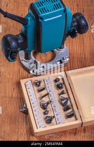 woodworking tools – set of roundover router bits in box and plunge pouter on old wooden board Stock Photo
