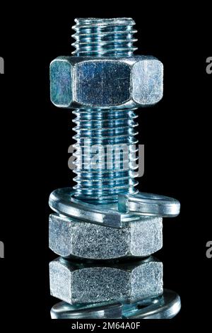 Threaded construction nut screwbolt spring washer on black surface. Stock Photo
