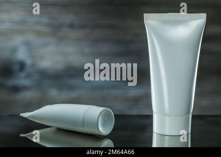 two white tubes skincare items on dark background Stock Photo