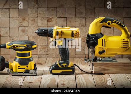 construction carpentry tools electric corded jigsaw cordless drill and wood sander on wooden background Stock Photo