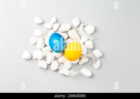 Ukrainian Easter Eggs painted Blue and Yellow on white rocks over gray background. National flag colors. Support Ukraine Stock Photo