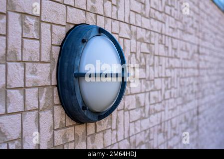 Round white outdoor wall light with metal frame guard Stock Photo
