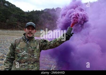 U.S. Air Force Tech. Sgt. Eric Mcnair a Survival, Evasion, Resistance, and Escape Specialist assigned to the 51st Operational Support Squadron on Osan Airbase, Republic of Korea, is seen holding a smoke grenade to act as a signal during  Joint Combat Search and Rescue training exercises, Pyeongchang, Republic of Korea, March 31, 2022. The team marked the extraction zone for the rotary winged aircraft to descend and hover to recover the isolated person. Stock Photo