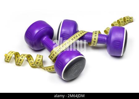 Dumbbells and measuring tape on white background. Stock Photo