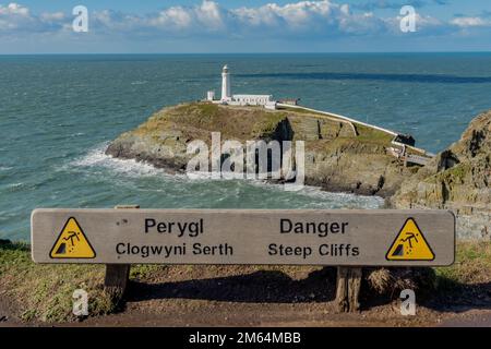 Panoramic photo of South Stack Lighthouse near Holyhead Anglesey. Danger steep cliffs warning sign with view behind Stock Photo