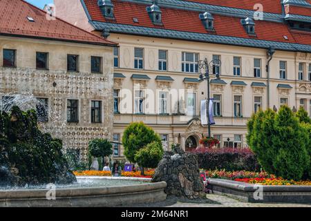 Banska Bystrica, Slovakia - August 17, 2021: view of SNP Square - colorful historic buildings, blooming flowers, green bushes, fountain and people wal Stock Photo