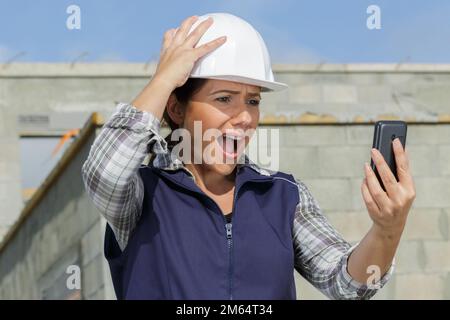 scared female builder talking on the mobile phone Stock Photo