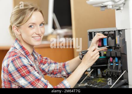 happy female technician fixing a printer Stock Photo