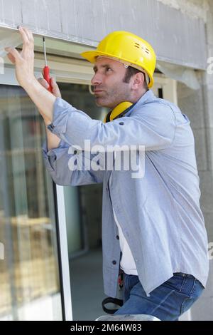worker fasten the handle to a plastic window Stock Photo