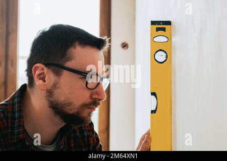 Builder at construction site measuring plumb with focus on spirit level Stock Photo
