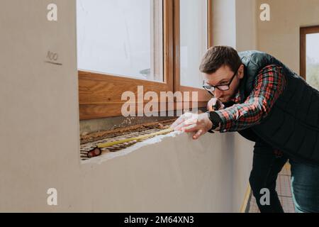 Carpenter measuring window ledge in new house Stock Photo