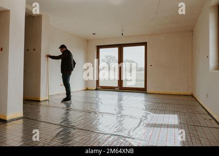 Builder measuring wall with tape Stock Photo
